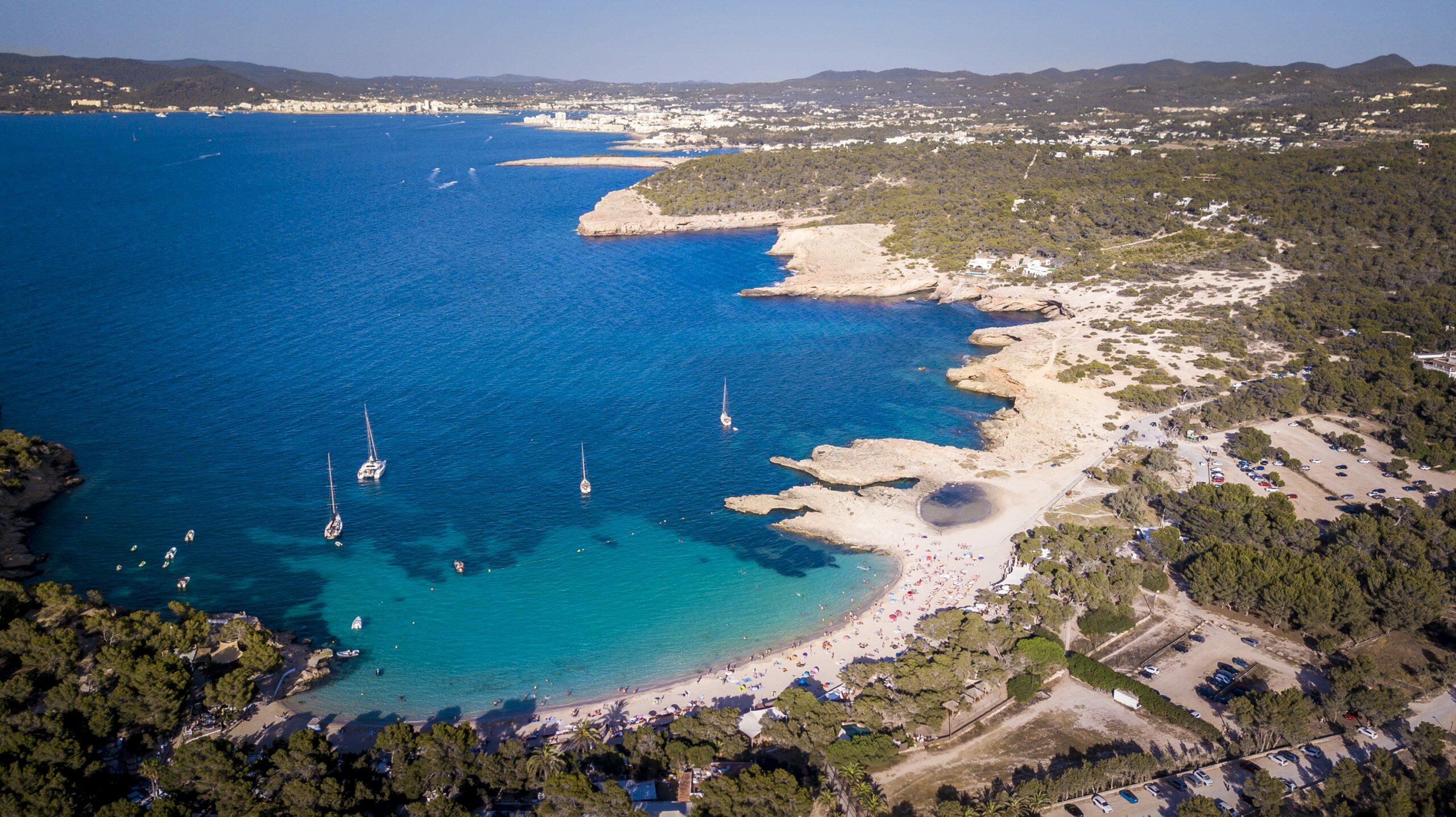 Vista aerea di Cala Bassa a Sant Josep de sa Talaia, Ibiza, con barche a vela e una spiaggia sabbiosa