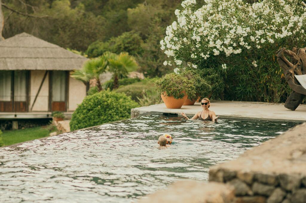 Piscina e giardino mediterraneo a Villa Paradiso a Ibiza, con ospiti che si godono l'acqua.
