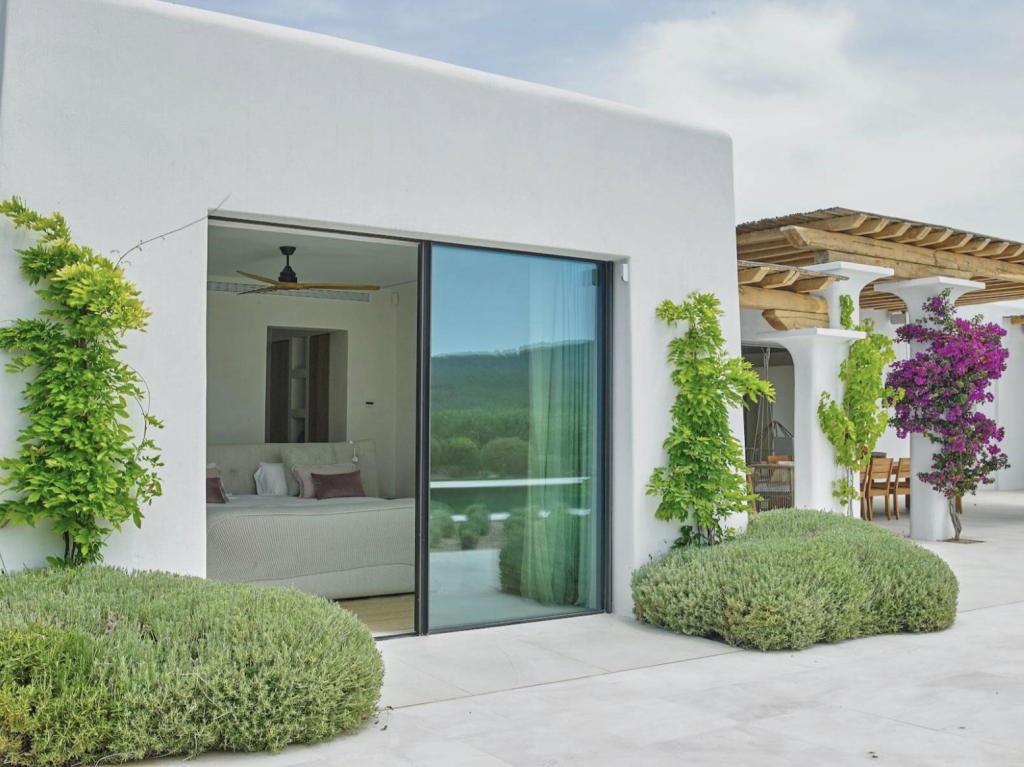 Villa Blakstad a Ibiza con pareti imbiancate a calce, porte scorrevoli in vetro, giardino paesaggistico e terrazza coperta.